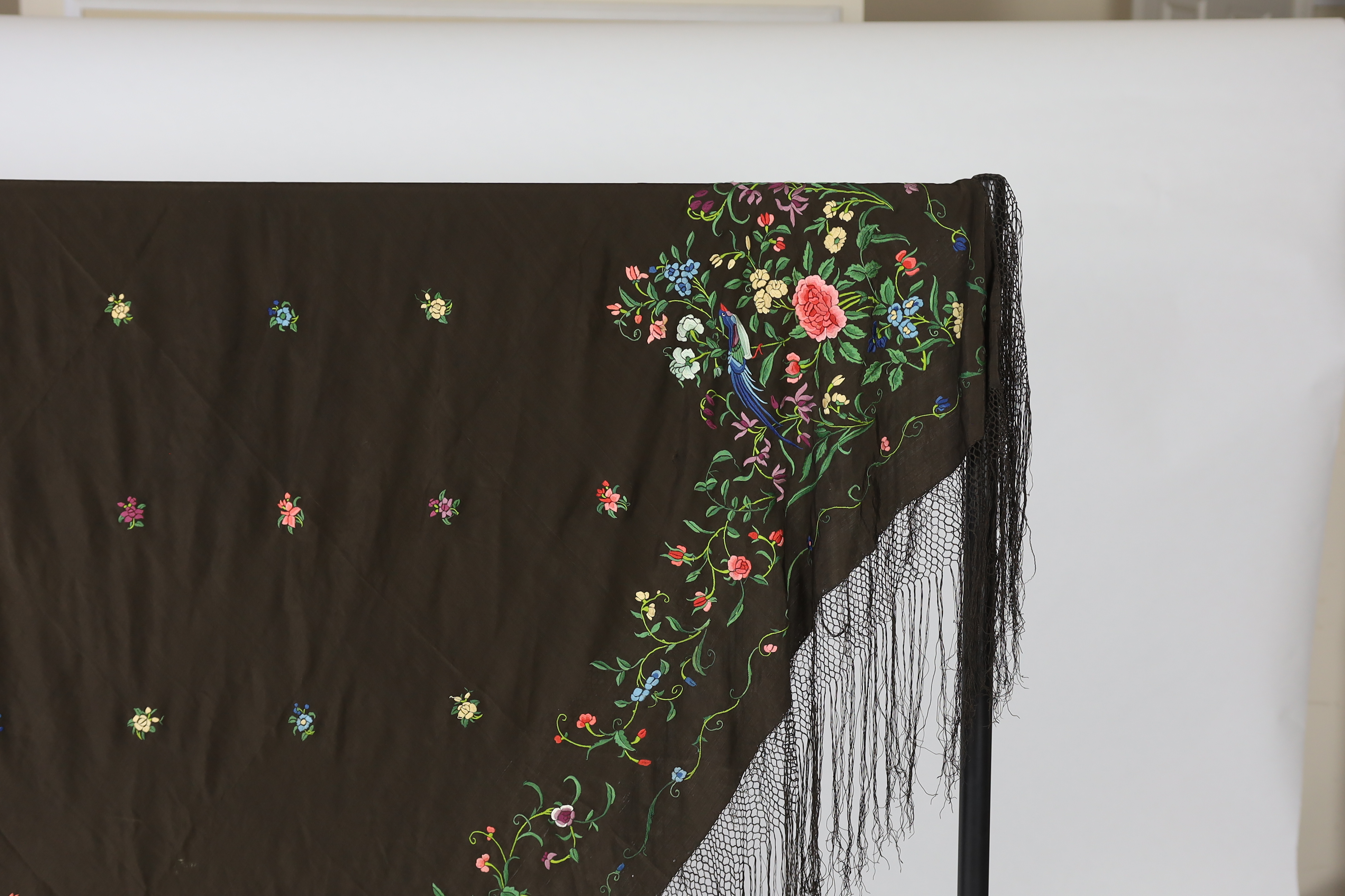 A Chinese silk shawl, circa 1900, embroidered with polychrome threads with birds and flowers against a black silk ground, 164cm sq.